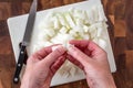 WomanÃ¢â¬â¢s hands separating an onion, white cutting board on wood butcher block